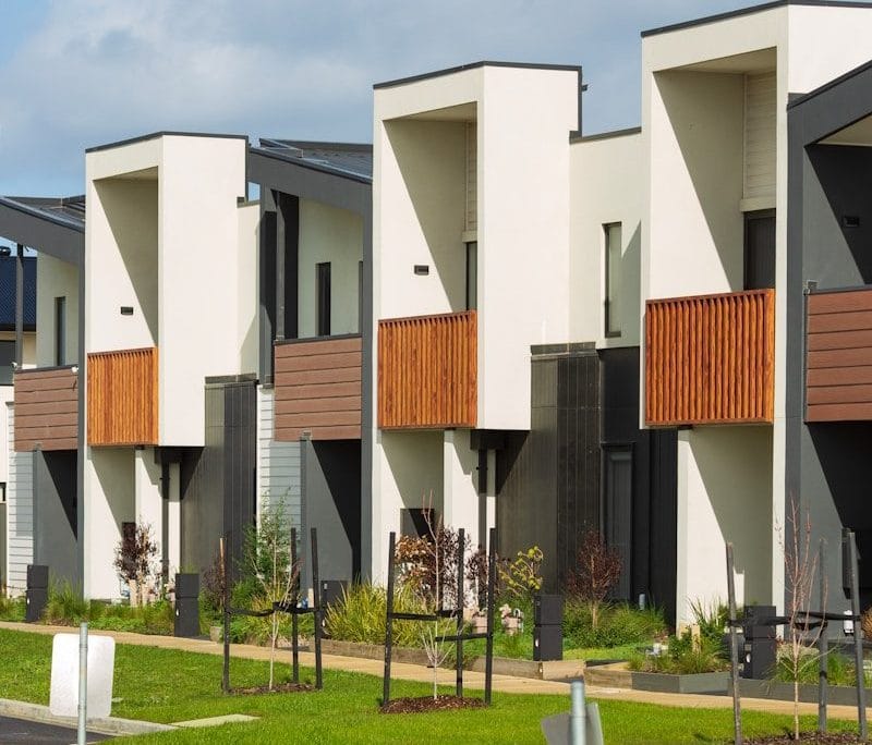 Modern townhouses with wooden balconies under a cloudy sky